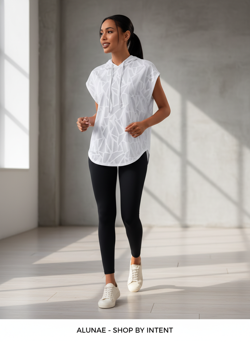 Woman in a cream oversized short sleeve sport hoodie, captured mid-movement in a minimalist setting.